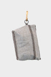 The Linen Trail- is a gray linen bag with decorative brown stitching, made from upcycled designer linen, shown folded and hanging from a brass hook against a plain white background.