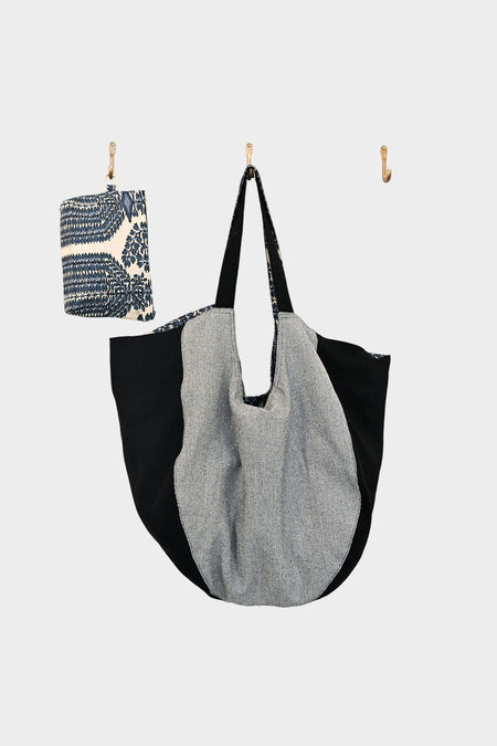 On the middle hook hangs a large, round Bella Bag with black and gray panels. The left hook features the Indigo Harmony accessory (AVAILABLE AT ABADIR, contact for details), and the right hook is empty against a white background.