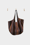 A large, soft Mesa Stripe tote (AVAILABLE AT ABADIR—contact for details), made from upcycled designer upholstery in blue, orange, and brown dotted patterns, hangs from a hook on a white wall between two empty hooks.