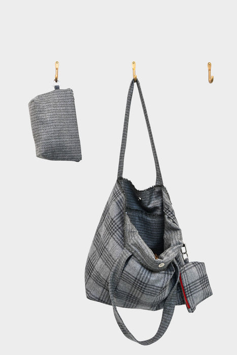 A gray AVAILABLE AT PIERRE LAFOND city flannel bag with a subtle checkered pattern hangs on a hook next to a matching folded pouch, both set against a plain white background.