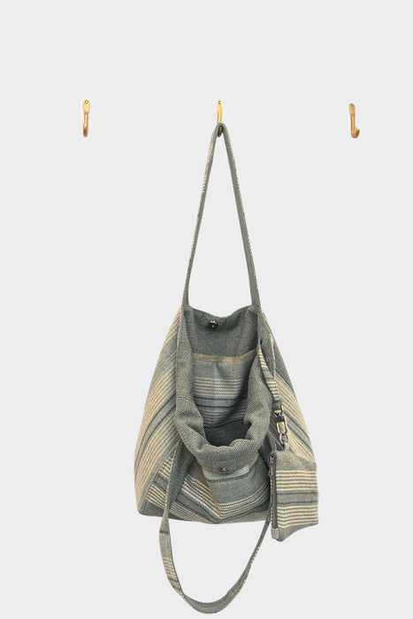 The Sage and Smoke bag, available at Abadir (contact for details), features soft sage stripes, long straps, multiple pockets, and is crafted from upcycled designer upholstery for a unique, eco-friendly touch.