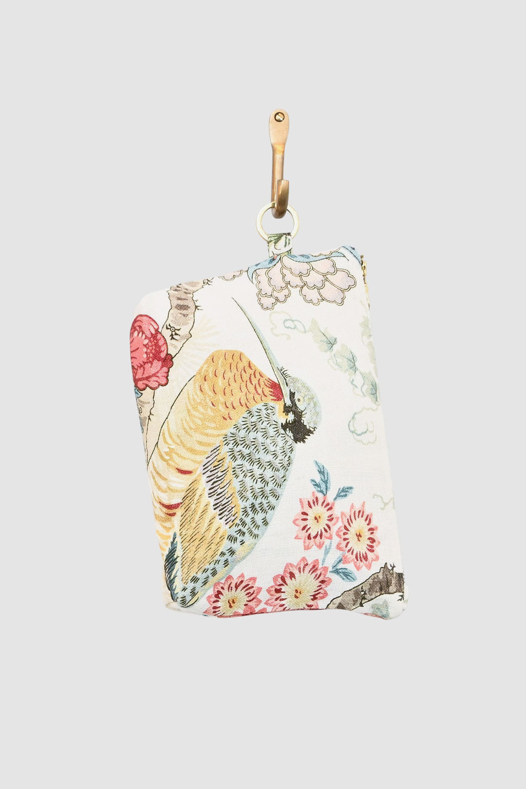 The Mightie Mouse Pouch- Ibis Garden features a small floral and bird print in yellow, red, and blue, hanging by a tan leather loop with a gold clasp against a plain light gray background.