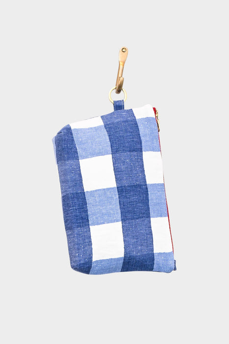 Gingham Coast: A small blue and white checkered gingham pouch with a red zipper and tan leather strap featuring a gold clasp, photographed on a plain light gray background.