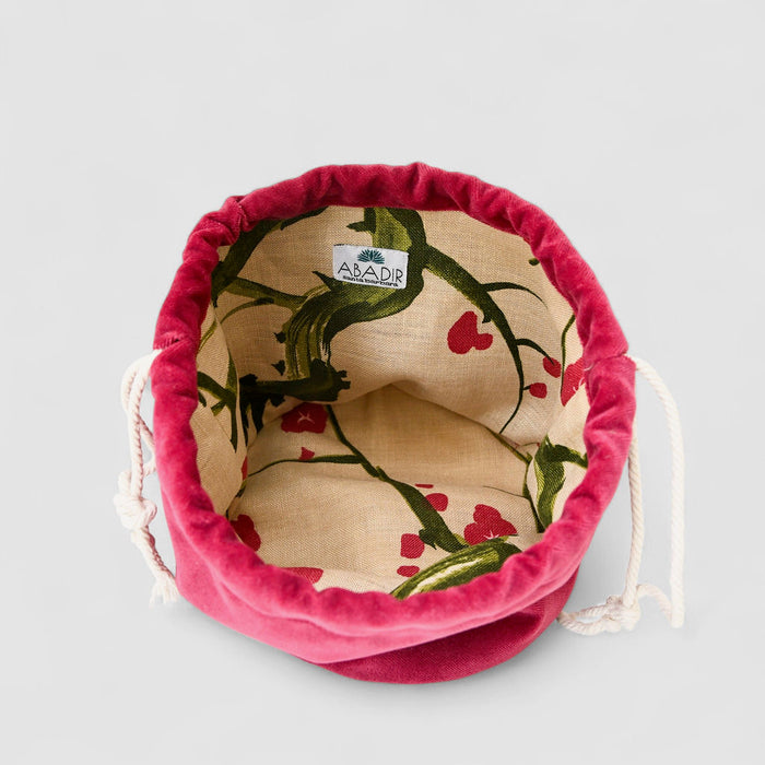 The Poppy Bag Fuscia Velvet is a fuchsia velvet drawstring pouch with a deep red exterior, cream upcycled linen lining, and green-red botanical print, featuring an inner ABADIR label.