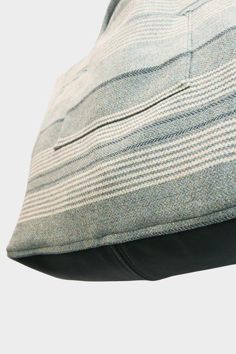 Close-up of the "Sage and Smoke" bag, AVAILABLE AT ABADIR. Crafted from upcycled designer upholstery in light blue, gray, and cream stripes, it features a visible pocket and green smoke leather base against a plain white background. Contact for details.