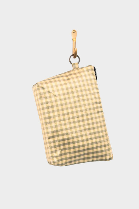 The Meadow Check pouch in beige and light green gingham hangs from a wooden hook against a plain light gray background.
