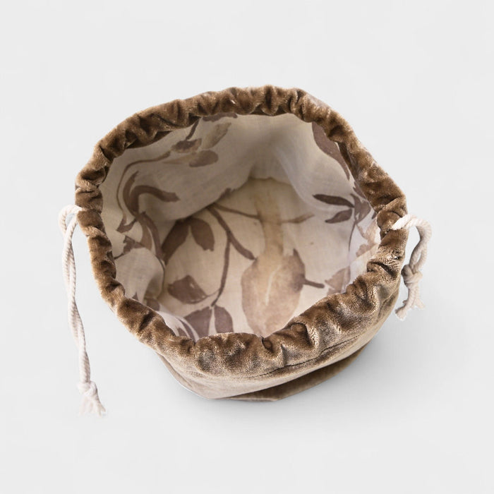 The Poppy Bag- Cocoa Velvet Vine is a small pouch made from upcycled designer cocoa velvet, featuring a brown leaf pattern on its cream lining and white drawstrings on both sides.